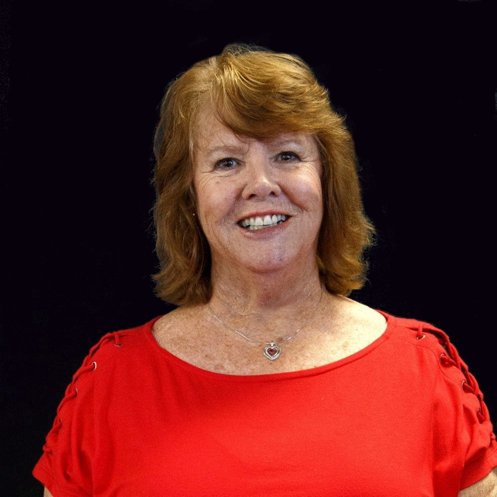 A woman in red shirt smiling for the camera.