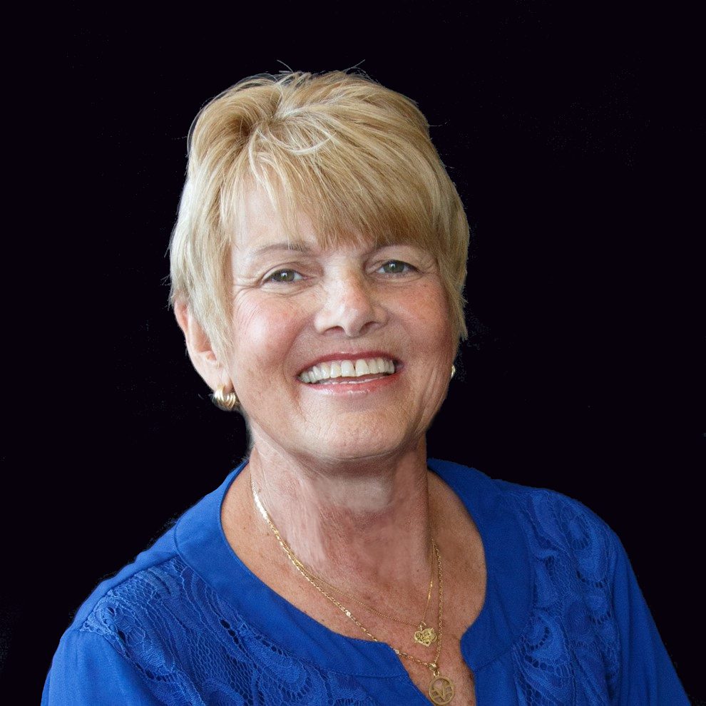 A woman with blonde hair and blue shirt smiling.