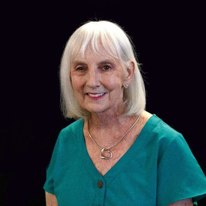 A woman with white hair wearing a green shirt.